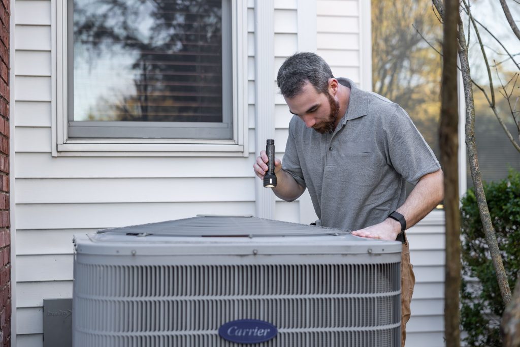 A technician inspects an outdoor HVAC unit for maintenance