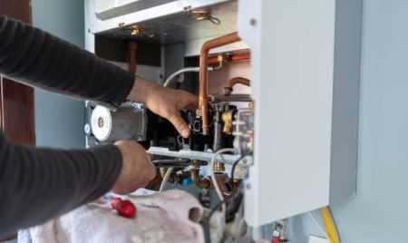 Technician Repairing Natural Gas Combi Boiler At Home