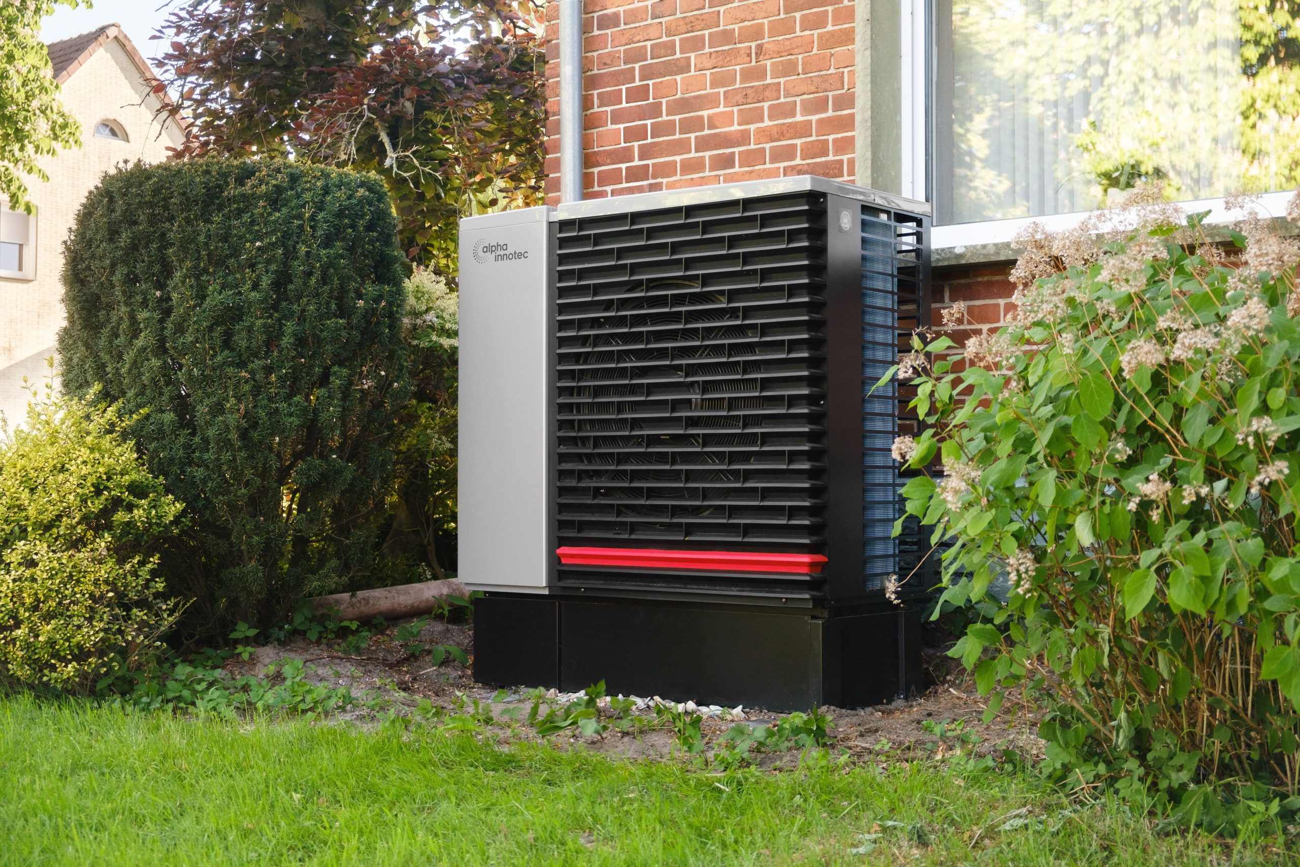 A residential heat pump outdoor unit installed beside a home